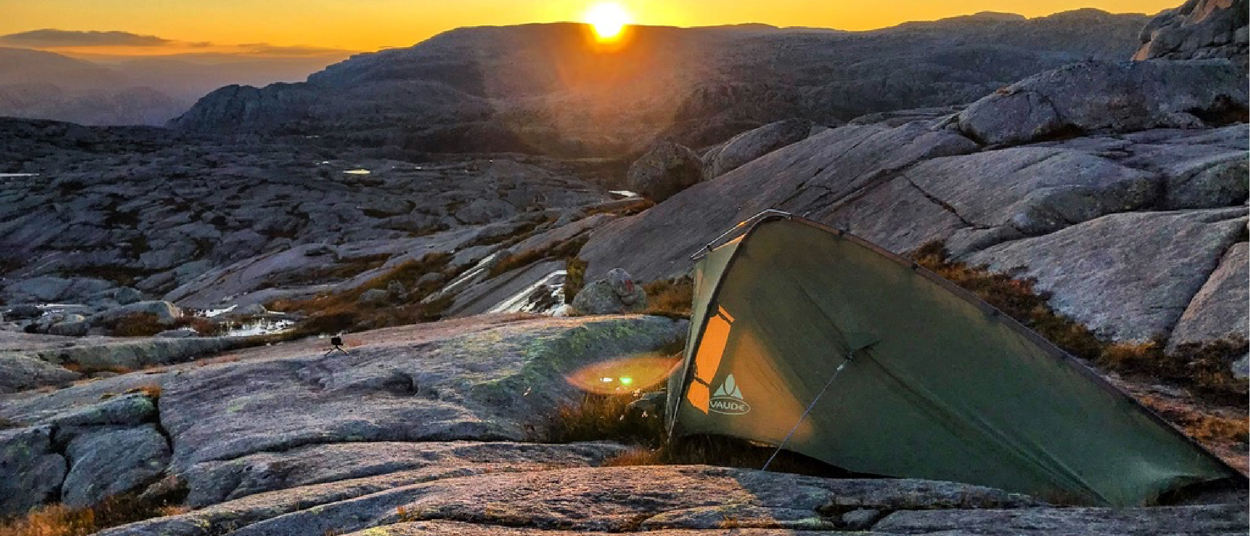A vast dusk landscape with a tiny shelter in the distance